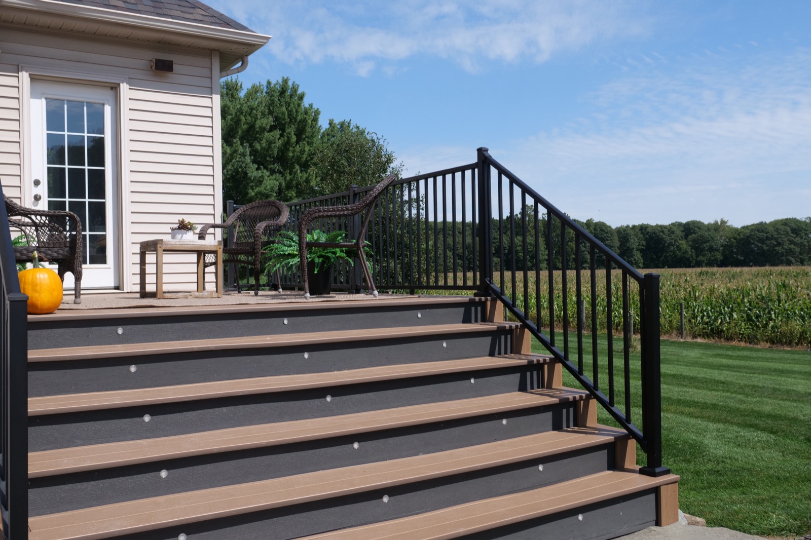 Composite deck stairs with black aluminum railing beside a cornfield at a rural Northern Indiana home