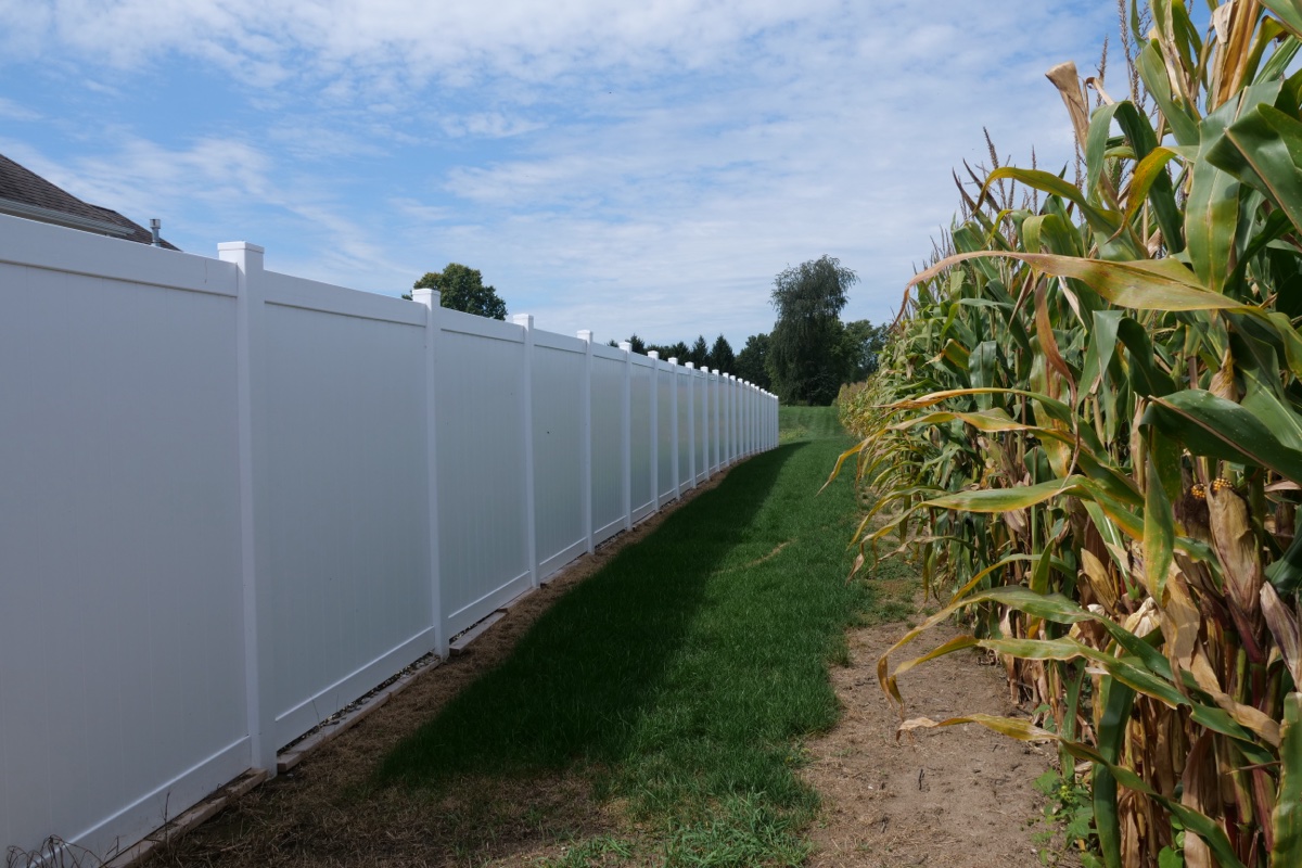 White vinyl privacy fence running the length of a Kosciusko County property line