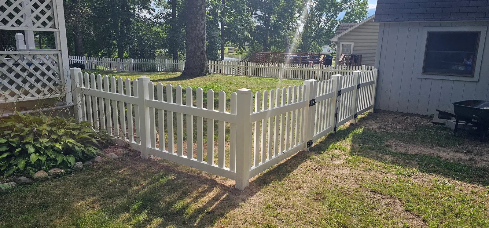 White vinyl picket fence with a scalloped top line and black gate hardware running through a Warsaw back yard from our Lincoln Park picket job