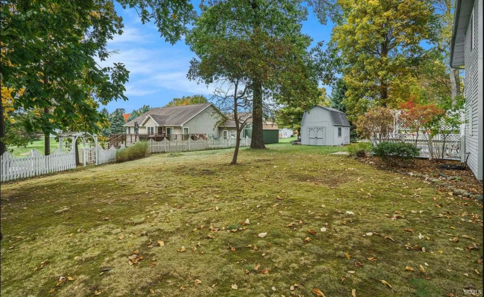 Open back yard in Warsaw before installation, with a mature shade tree, a barn-style shed and no fence enclosing the lawn