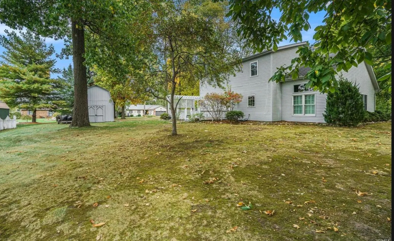 Second before photo looking across the unfenced yard toward the two-storey house and the pergola-covered deck